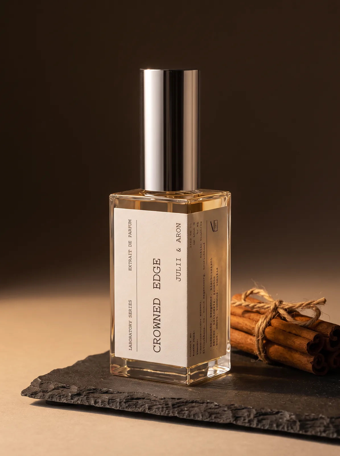 Crowned Edge Parfum von Julii & Aron – Flakon auf Schiefer mit Zimtstangen